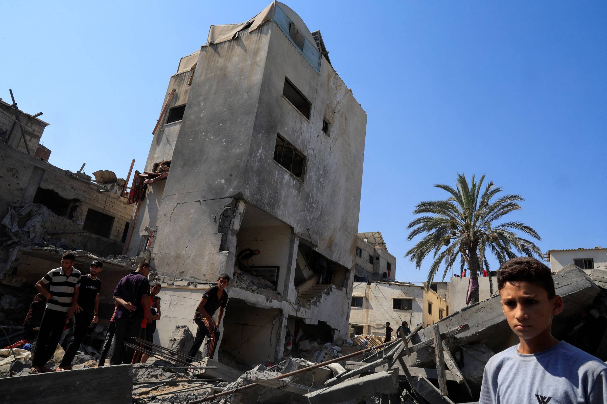 فلسطينيون يعاينون مكاناً استهدفه القصف الإسرائيلي بدير البلح وسط قطاع غزة السبت (رويترز)