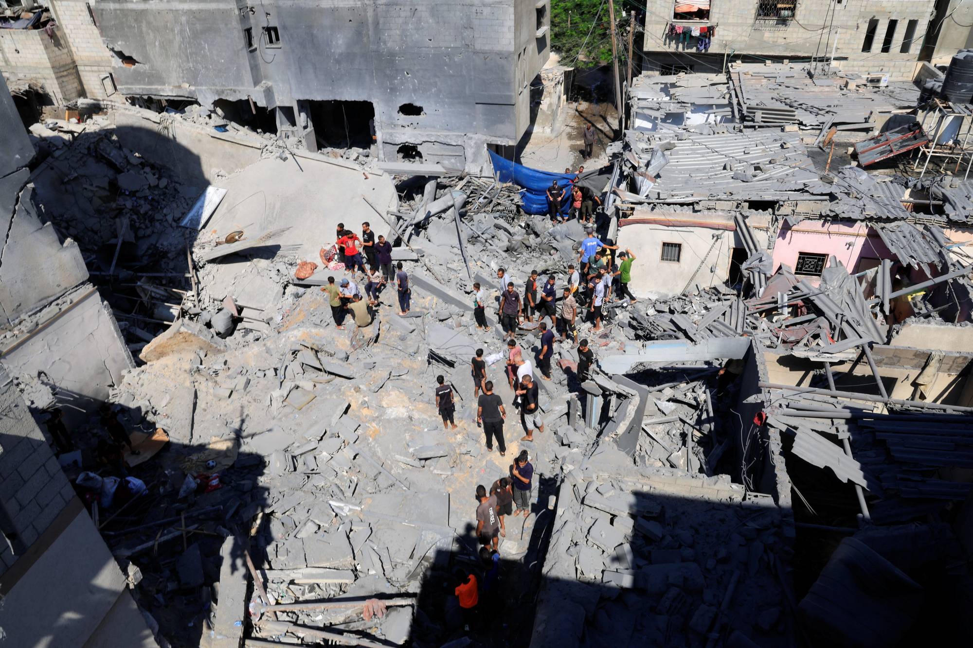 فلسطينيون يعاينون مكاناً استهدفه القصف الإسرائيلي بدير البلح وسط قطاع غزة السبت (رويترز)